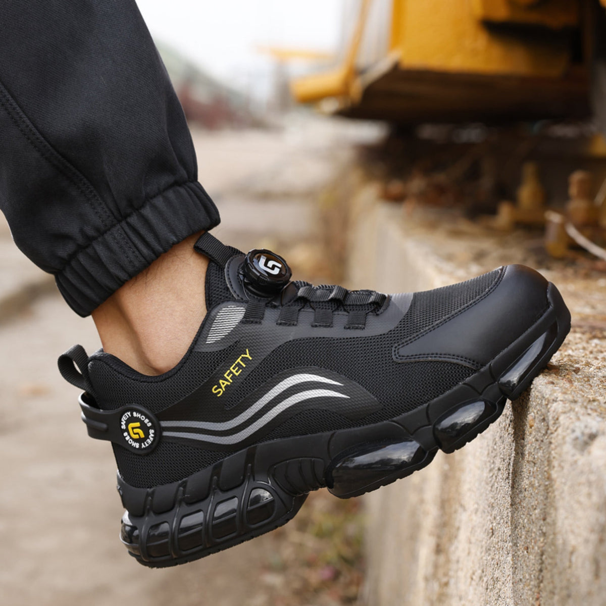 Worker wearing black work sneakers beside construction equipment